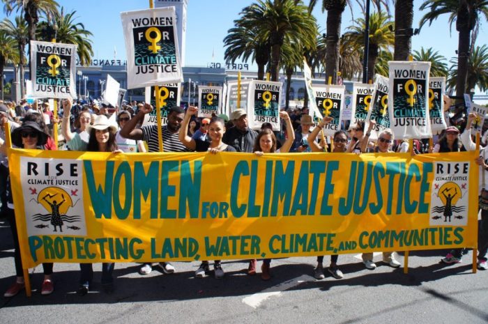 A group of climate activists on the street. They are holding a large cloth poster that reads 