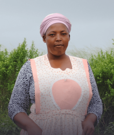 A Black woman farmer in the middle of a field is looking straight at the camera.