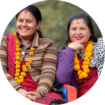 Two women, garlanded, smiling and looking at the camera.